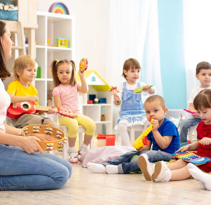Children playing instruments with teacher.