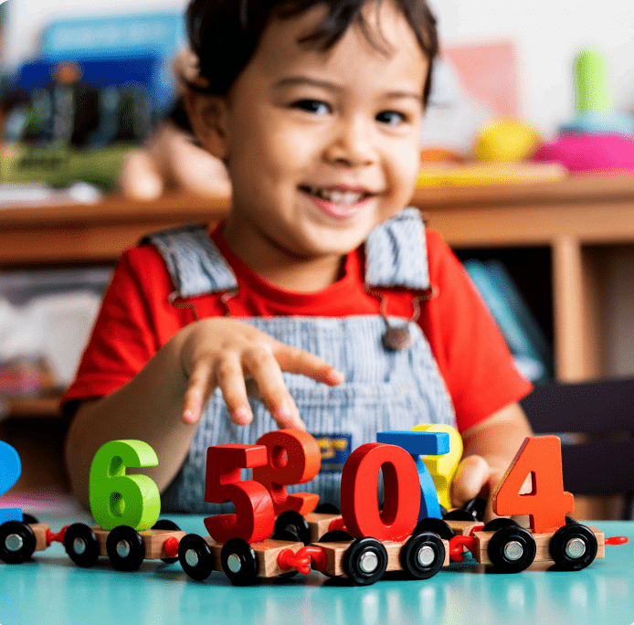 Child playing with a toy train featuring numbered cars.